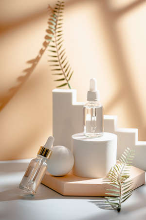 Glass cosmetic bottle with oil or serum for skin care on special podium on apricot color background. Natural skin care concept. Harsh shadowsの写真素材