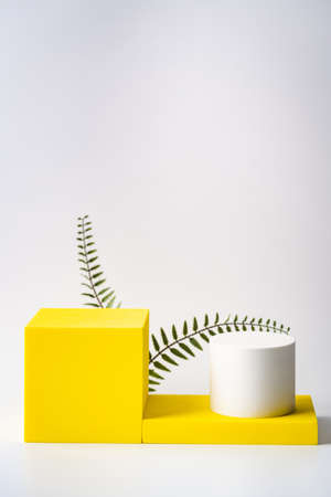 Cosmetics product advertising stand. Exhibition yellow podium with geometric shapes on a white color background. Empty pedestal to display product packaging. Mockupの写真素材