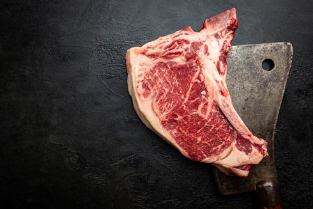 Raw fresh meat T-bone beef Steak and butcher knife on black background, top viewの写真素材