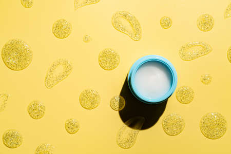 Jar of cosmetic cream for skin on yellow background, top view with copy space