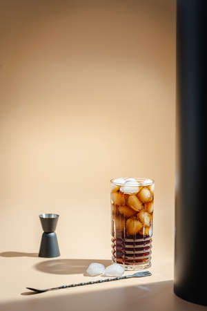 Soft drink Cola or cuba libre cocktail in a glass with ice cubes isolated on light orange background