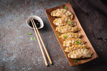 Asian dumplings with soy sauce, sesame seeds and microgreens. Traditional chinese dim sum dumplings on wooden plate.の写真素材