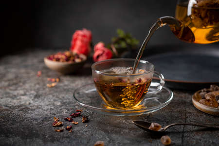 herbal flower tea from the petals of rose in a glass cup on dark gray backgroundの写真素材