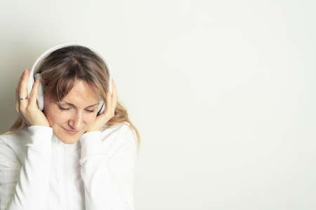Portrait of smiling pretty woman enjoying music with white headphones on white background
