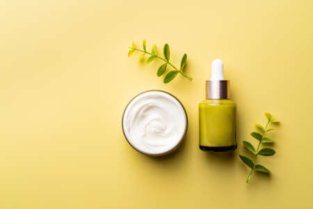 Set of natural cosmetics for face care serum bottle and cream on yellow background, top viewの写真素材
