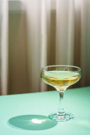 Wine Glass of white wine with bright shadows over green backgroundの写真素材
