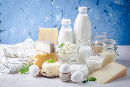 Fresh dairy products, milk, cottage cheese, eggs, yogurt, sour cream and butter on blue backgroundの写真素材