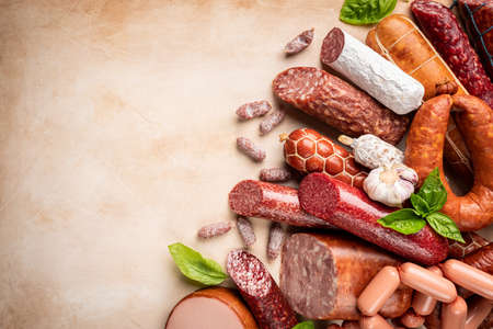 Set of different types of sausages, salami and smoked meat with basil and spices on light background. Top view.の写真素材