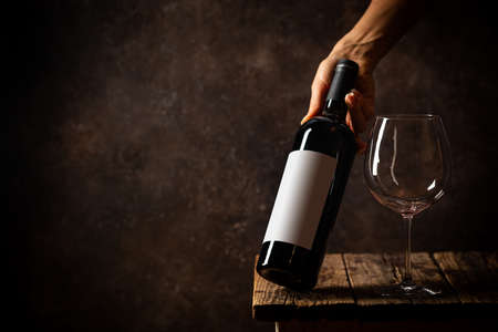 Glass of red wine with bottle against rustic dark wooden backgroundの写真素材
