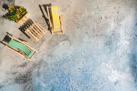 Toy wooden sun loungers on beach imitation background, top view. Relaxation and travel concept.の写真素材