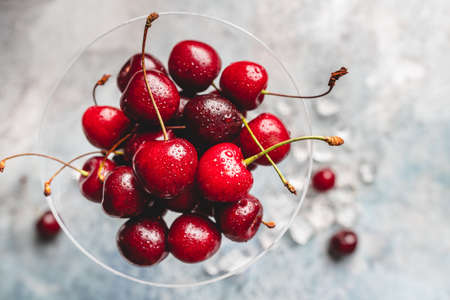 Top view of a ripe sweet cherry in a glass on light blue backgroundの写真素材