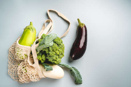 Eco friendly mesh bag with organic green vegetables on gray background. Flat lay, top view. Zero waste, plastic free concept. Healthy clean eating diet and detoxの写真素材