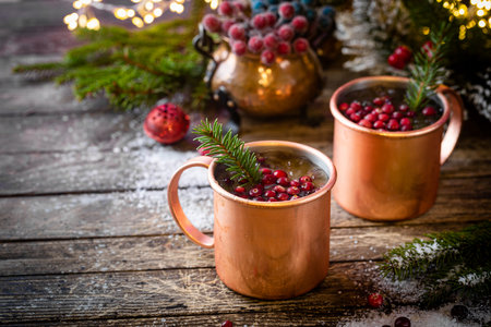 Mulled wine with cranberry in copper mug with christmas decorations on wooden tableの写真素材