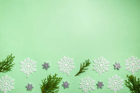 Christmas composition made of snowflakes and thuja branches on green background, top view. Winter...