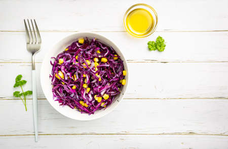 Fresh coleslaw salad made of shredded red and white cabbage and corn on white wooden background, top viewの写真素材