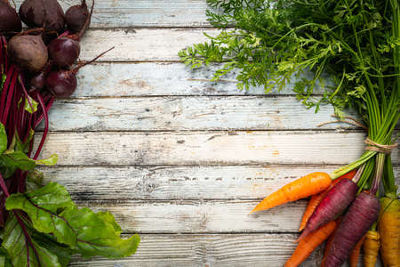 Fresh organic carrots and beetroot with leaves, root vegetables over wooden background, top viewの写真素材