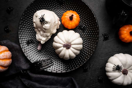 Creative flat lay autumn composition. Pumpkins and spiders over black background, top view. Template fall, thanksgiving or halloween cardsの写真素材