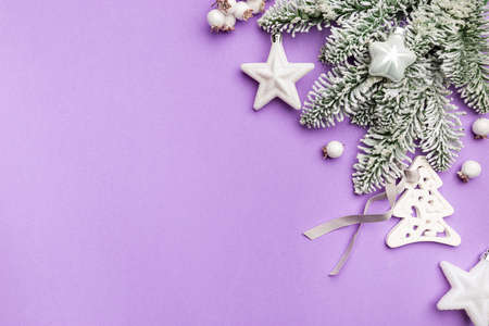 Christmas holidays composition with white christmas decorations and fir tree branches on purple background with copy space, top viewの写真素材