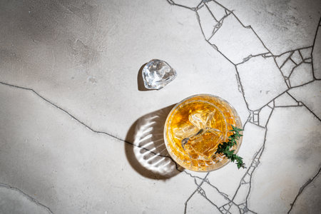 Glass of whiskey with ice on gray stone background. Top view with copy spaceの写真素材