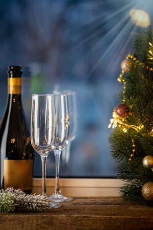 Empty crystal glasses and a bottle of champagne in front of the window. Concept of new year and Christmas holidays.の写真素材