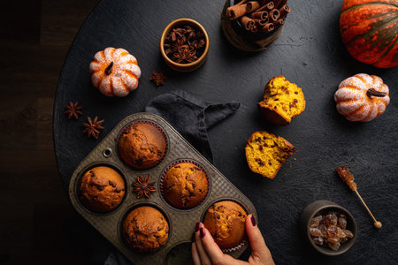 Homemade autumn pumpkin muffins with cinnamon and chocolate on dark background, top viewの写真素材