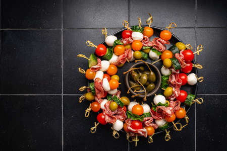 Appetizer and refreshment set. Plate of canapes with vegetables, cheese, salami and olives decorated...