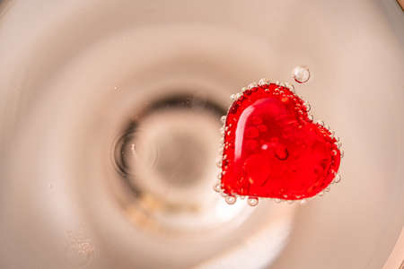 Valentines Day background or greeting card. Red hearts inside glass of champagne close up with free spaceの写真素材