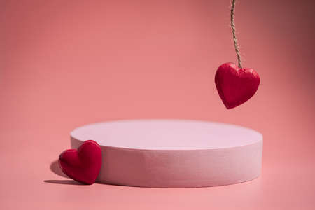 Pink empty podium with red heart over pastel background to show cosmetic products. Minimal romantic backdrop with stand for branding and presentation on Valentines Day.の写真素材