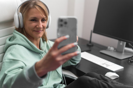 Young woman or blogger using social media messenger on modern mobile phone, chatting with friends, having video call or recording video for blogの写真素材