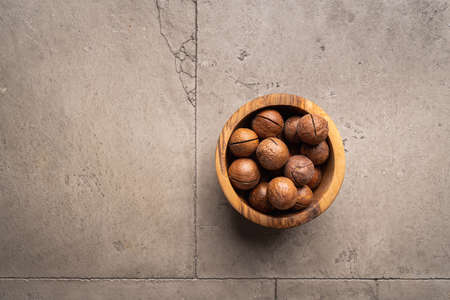 macadamia nuts in a bowl on gray stone background top view with copy space. Healthy snack food.