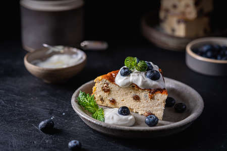 Baked homemade cottage cheese casserole or pudding with raisins serving with blueberry and sour...