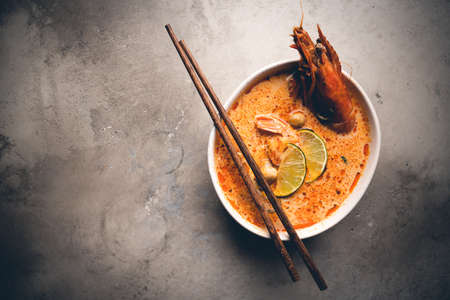 Tom Yam kung Spicy Thai soup with shrimp, seafood, coconut milk and chili pepper in a bowl, top view with copy spaceの写真素材