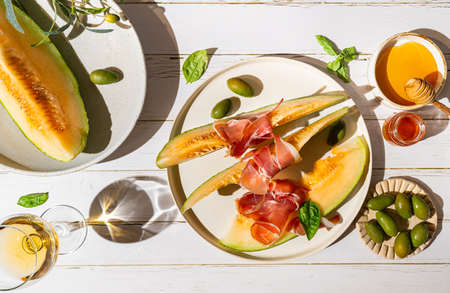 Jamon serrano, ham or prosciutto with melon and olives, a traditional Spanish and Italian appetizer on plate, top viewの写真素材