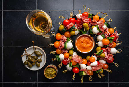 Appetizer and refreshment set. Plate of canapes with vegetables, cheese, salami and olives decorated for party table, top viewの写真素材