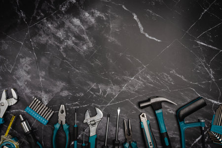 Assorted Hand Tools Laid Out on black marble background, top view with space for text