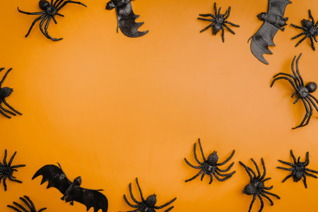 A modern greeting card for Halloween. Cobwebs, spiders, bats, a ghost on a fashionable orange background. A banner with a place to copy the text. Top view. Flat Lay.の写真素材