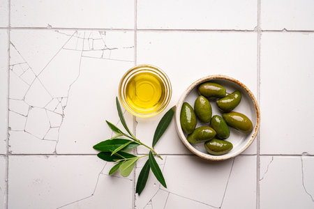 Green olives and olive oil on white tile background, top viewの写真素材