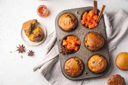 Homemade spicy pumpkin muffins or cupcakes with chocolate on a metal rack, top view. Autumn dessert. Selective focusの写真素材