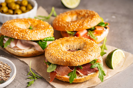Variety of Bagel sandwiches with ricotta, prosciutto or chicken ham or salmon and microgreens, bagel with ham for breakfast on gray background, close up. Healthy breakfast food.の写真素材