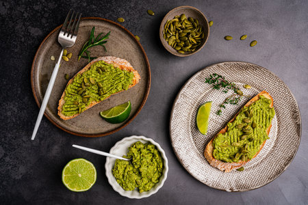 Toast with fresh avocado, herbs and seeds with lemon slices on dark background. Healthy eating and wholesome Breakfast, top viewの写真素材