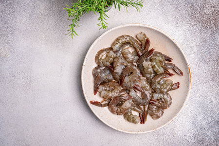Raw whole fresh uncooked prawns or shrimps in a white plate on a white background. Top view with copy space.の写真素材