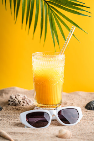 Colourful orange cocktail in a tall glass on a sandの写真素材