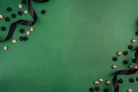 Black Ornaments and Stars Frame with Gold Ribbon on Greenの写真素材
