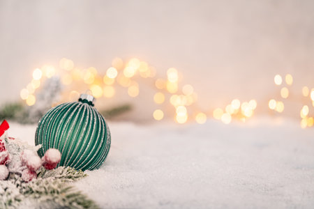 Green Christmas Ornament with Silver Ribbon on Snowy Surfaceの写真素材