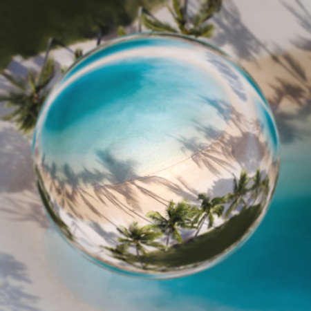 Reflection of palm trees in crystal ball on water surface. Selective focus.の写真素材