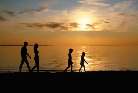 Family Strolling On Beach At Sunsetの写真素材