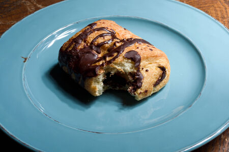 chocolate croissant with bite on blue plateの写真素材