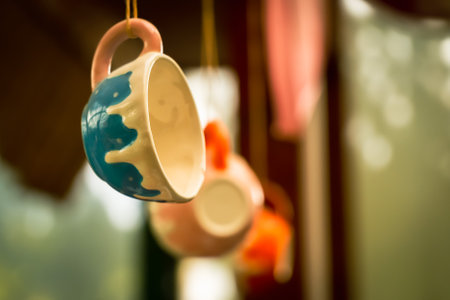 Colorful ceramic cups and saucers hanging on the wall in cafeの写真素材