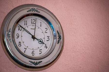 decorative metal wall clock hanging on a stucco wall isolated