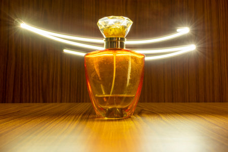High class perfume bottle isolated on wooden background with light trail effectの写真素材